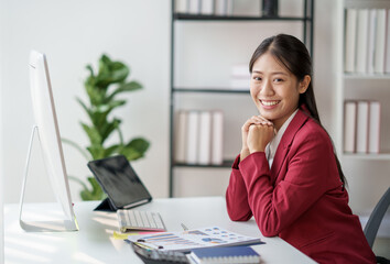 Poster - Confident Asian businesswoman sitting on desk in office