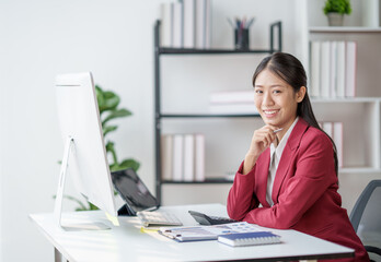 Poster - Confident Asian businesswoman sitting on desk in office