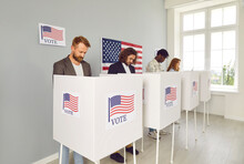 Group Of Diverse American Citizens Voting At Polling Station During USA Presidential Elections. Several People Make Choice And Vote For Different Candidates In Booths With US Flags. Democracy Concept