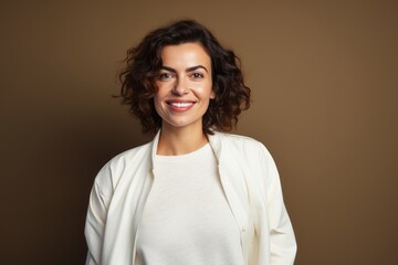 Portrait of a happy young woman smiling at camera on brown background