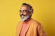 © Anne-Marie Albrecht - Portrait of a happy Indian senior man in eyeglasses smiling against yellow background