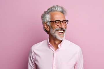 Wall Mural - Portrait of happy senior man in eyeglasses smiling at camera while standing against pink background