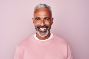 Wall Mural - Portrait of a handsome mature man smiling at the camera while standing against pink background