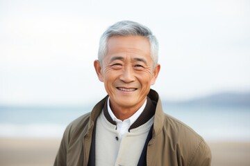 Wall Mural - Close-up portrait of a Chinese man in his 60s in a beach background wearing a chic cardigan