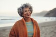 © Leon Waltz - Medium shot portrait of a Nigerian woman in her 50s in a beach background wearing a cozy sweater