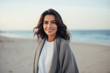 Wall Mural - Medium shot portrait of a Saudi Arabian woman in her 30s in a beach background wearing a chic cardigan