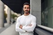 © Leon Waltz - Portrait of handsome man with crossed arms looking at camera and smiling while standing outdoors