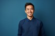 © Leon Waltz - Portrait of a happy young asian man smiling against blue background