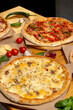 © Светлана Мищенко - Set of different baked pizzas on a wooden table. Menu for restaurant, pizzeria. Assortment of pizzas.