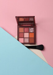 Wall Mural - Eye shadow palette with makeup brushes on pink blue background. Beauty concept