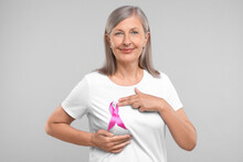 Beautiful Senior Woman With Pink Ribbon On Light Grey Background. Breast Cancer Awareness