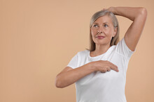 Beautiful Senior Woman Doing Breast Self-examination On Light Brown Background. Space For Text