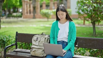 Sticker - Young chinese woman closing laptop relaxed on bench at park