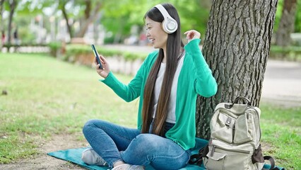 Canvas Print - Young chinese woman listening to music dancing at park