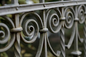 Poster - Close-up shot of a metal wrought fence set in a natural park setting with greenery in the background