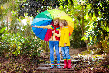 Wall Mural - Child playing in autumn rain. Kid with umbrella.