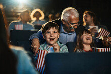 Grandfather And Grandchildren Watching A Movie And Eating Popcorn In A Movie Theater