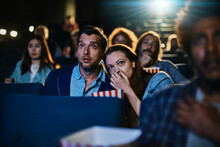 Young Couple Watching A Scary Horror Movie In A Movie Theater
