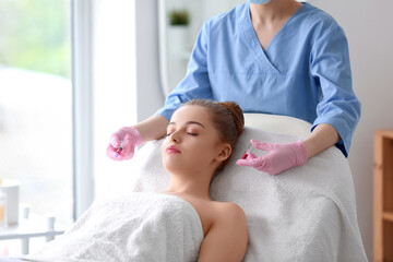 Wall Mural - Young woman receiving injection in beauty salon. Skin care concept