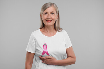 Poster - Beautiful senior woman with pink ribbon on light grey background. Breast cancer awareness