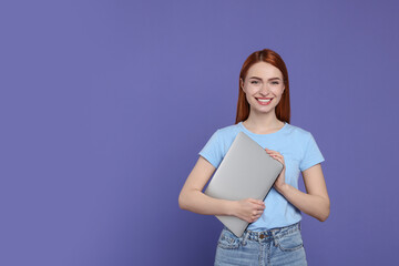 Canvas Print - Smiling young woman with laptop on lilac background, space for text