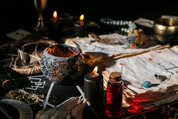 Witch's magic attributes with spell book on dark background, closeup