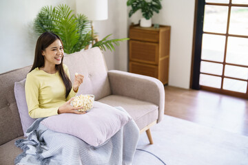 Wall Mural - Asian woman Watching smart TV and using remote controller Hand holding television audio remote control at home with the remote control television