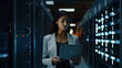 © AspctStyle - Successful young female data center it specialist using a digital tablet while working in a server room