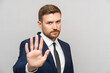 © DimaBerlin - Man businessman gestures to stop. Young Caucasian bearded business guy in suit shows open palm meaning stop enough urging to avast. Fatigue from annoying office rules, protest, desire to change system