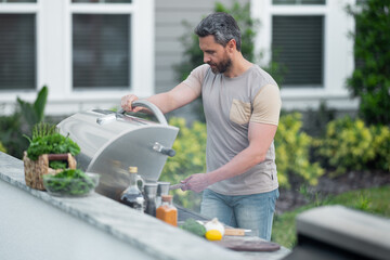 Wall Mural - Grill and barbecue cook. Chef with BBQ cooking tools. Barbecue and grill. Picnic barbecue party. Chief cook with utensils for barbecue grill. Barbeque on holiday picnic. Man grilling a steak on BBQ.