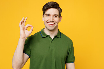 Wall Mural - Young smiling cheerful fun cool happy caucasian man he wears green t-shirt casual clothes looking camera showing ok okay gesture isolated on plain yellow background studio portrait. Lifestyle concept.