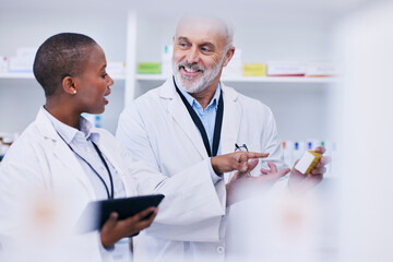 Wall Mural - Conversation, tablet and pharmacists checking medication for inventory, stock or medical research. Healthcare, medicine and senior chemist mentor teaching female pharmaceutical student with tech.