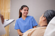 © NT_studio - Young caregiver or nurse care and talking patient elderly on bed for consoling in room at hospital ward, doctor examining and diagnostic with senior with friendly, medical and insurance concept.