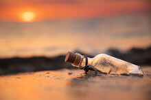 Message In The Bottle Against The Sun Setting Down