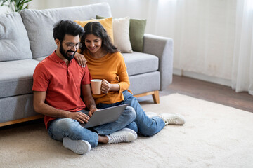 Poster - Weekend Leisure. Young Smiling Indian Couple Relaxing on Floor With Laptop