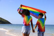 © naraichal - Women Lesbian couple in love on the beach with a rainbow flag, a symbol of the LGBTQ community