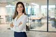 © insta_photos - Confident mid aged Latin professional business woman corporate leader, happy mature female executive, elegant lady manager of middle age standing in office arms crossed looking at camera, portrait.