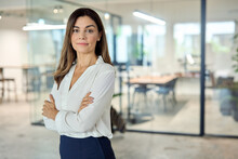 Confident Mid Aged Latin Professional Business Woman Corporate Leader, Happy Mature Female Executive, Elegant Lady Manager Of Middle Age Standing In Office Arms Crossed Looking At Camera, Portrait.