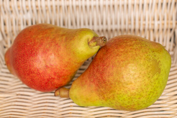 Two organic juicy pears in a basket, close-up.