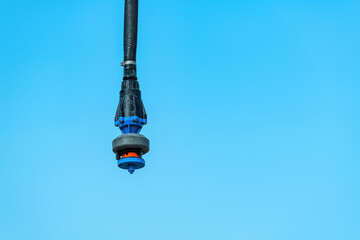 Agricultural irrigation water sprinkler outdoors against blue sky