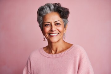 Group portrait of an Indian woman in her 50s against a pastel or soft colors background wearing a cozy sweater
