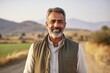 © Leon Waltz - Medium shot portrait of an Indian man in his 40s in his 40s wearing a cardigan in an indian rural landscape