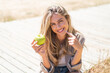 Young pretty blonde Uruguayan woman at outdoors holding an apple with happy expression