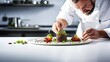 Chef in white uniform decorating dish with vegetables in modern kitchen
