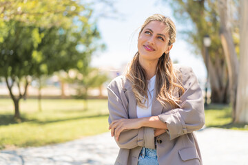 Young pretty blonde Uruguayan woman at outdoors looking up while smiling