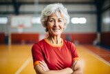 Portrait of smiling senior woman standing with arms crossed in sports hall