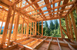 © anatoliy_gleb - Under-construction residential wooden frame home located near a forest. Commencement of a new construction project for a cozy house or a mountain cottage. Idea of contemporary ecological construction.