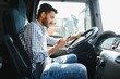© Serhii - Young handsome indian man using smart phone in his truck.