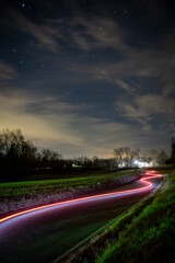 Wall Mural - long exposure of red light on the road with a starry night sky background