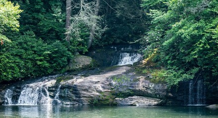 Poster - Picturesque waterfall flowing into a tranquil forest pond, surrounded by a lush canopy of foliage